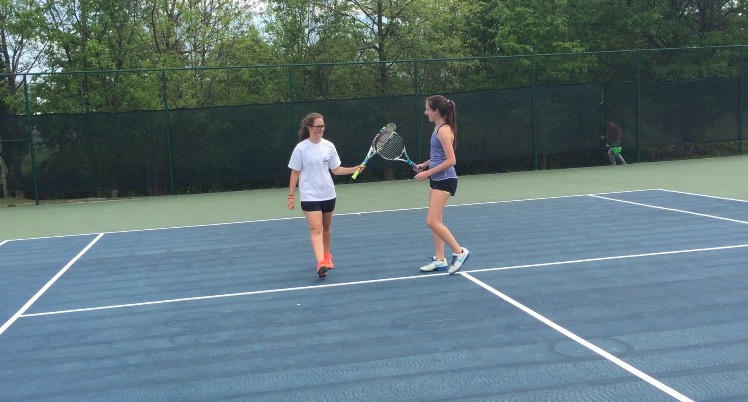 Doubles partners, junior Lisa Van Susteren (left) and senior Caroline Thoms (right), touch rackets after scoring a point during practice on April 19. 