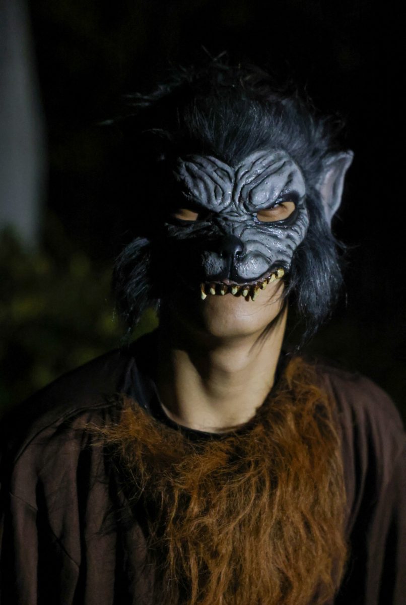 Anonymous student poses with a werewolf mask used for scaring the students on the trail