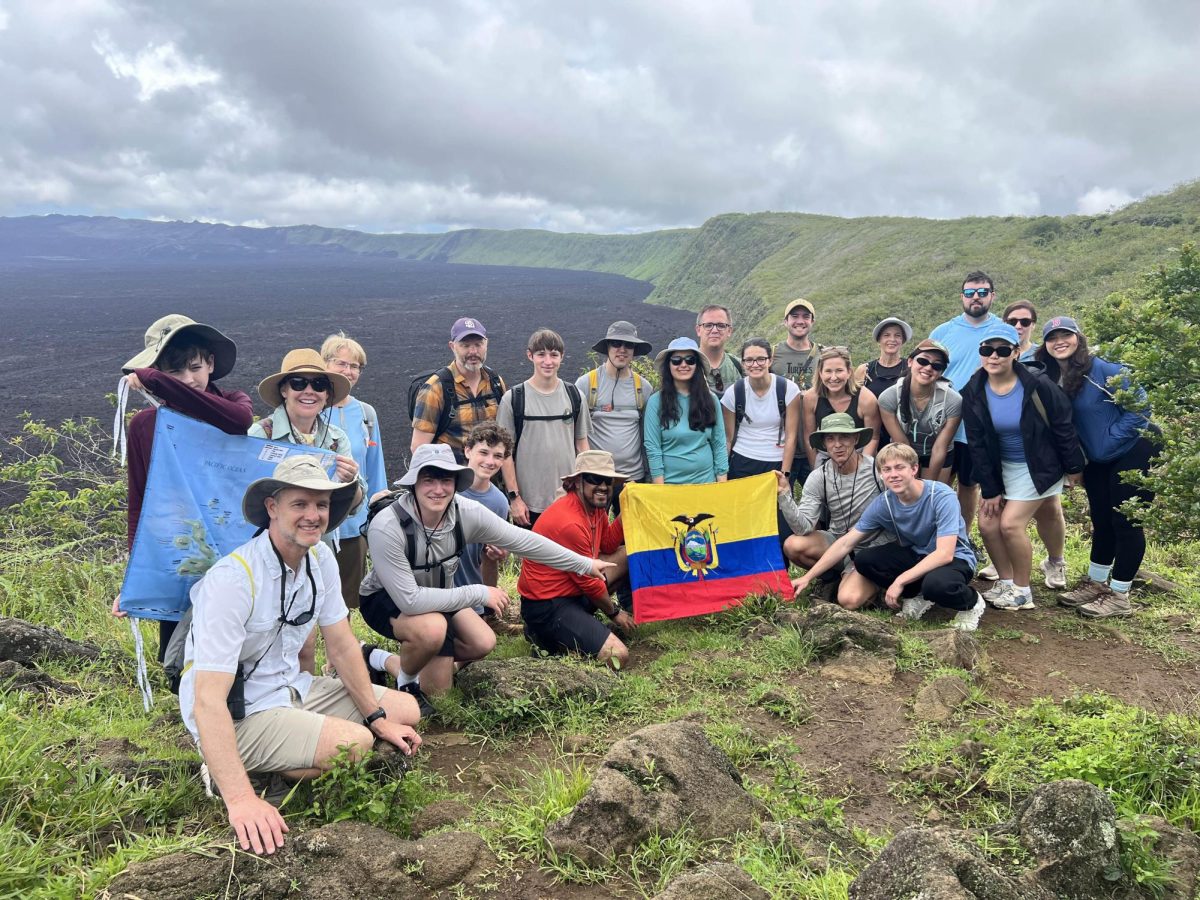 Students, faculty, and their families pose with the Ecuador flag while visiting Ecuador and the Galapagos Islands during spring break.