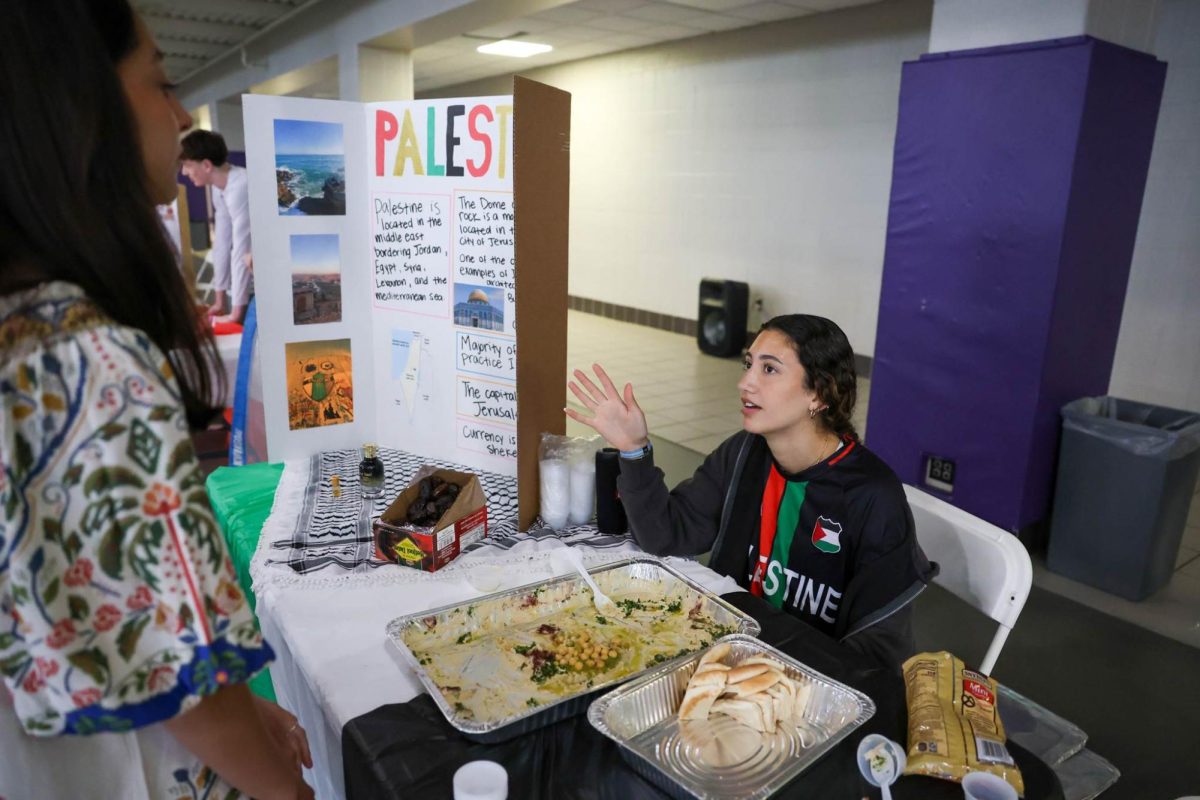 Senior Zain Elkhatib serving hummus and pita bread while sharing facts about Palestine to listeners.