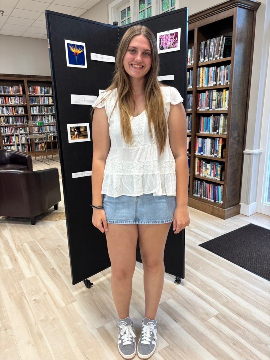 Senior Kaya Nadu displays her artwork in the upper school library along with other students.